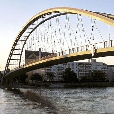 Brücke über einen breiten Fluss mit einem Stahlbogen und Drahtseilen