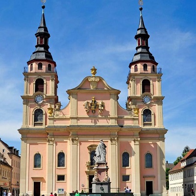 Barocke Kirche mit zwei Türmen, rosa Fassade und goldenen Verzierungen.