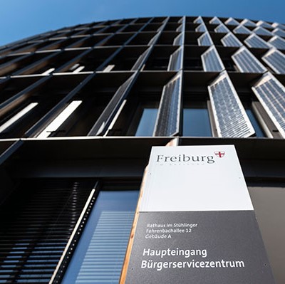Glasfassade des Bürgeramtes Freiburg mit Eingangsschild.