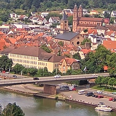 Luftaufnahme von Eberbach mit roten Dächern, zwei Kirchen und einer Brücke über einen Fluss.