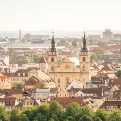 Luftansicht von Ludwigsburg mit einer Kirche mit zwei Türmen hinter ein paar Häusern und einer Baumreihe.