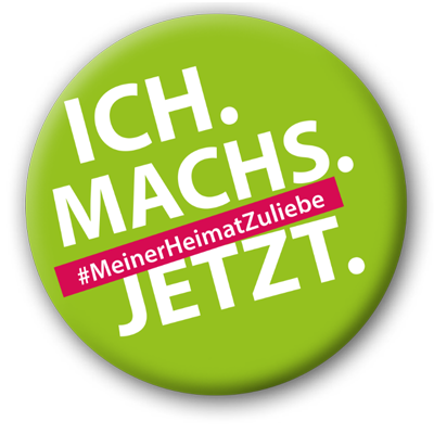 Runder grüner Button mit dem Text "ICH. MACH'S. JETZT." und dem Hashtag "#MeinerHeimatZuliebe" .