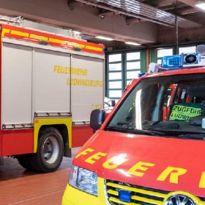 Rettungsfahrzeuge der Feuerwehr Ludwigsburg in einer Fahrzeughalle, mit leuchtend roten und gelben Farben.