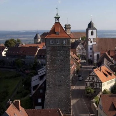 Blick auf eine historische Stadt im Hohenlohekreis mit einem markanten Turm und Fachwerkhäuser.