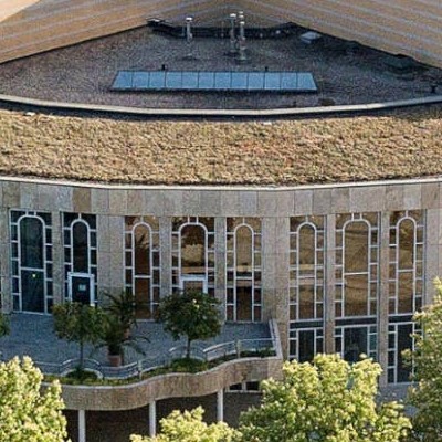 Fassade Forum Ludwigsburg mit einem flachen Dach, großen Glasfenstern und einer Terrasse mit Bäumen.