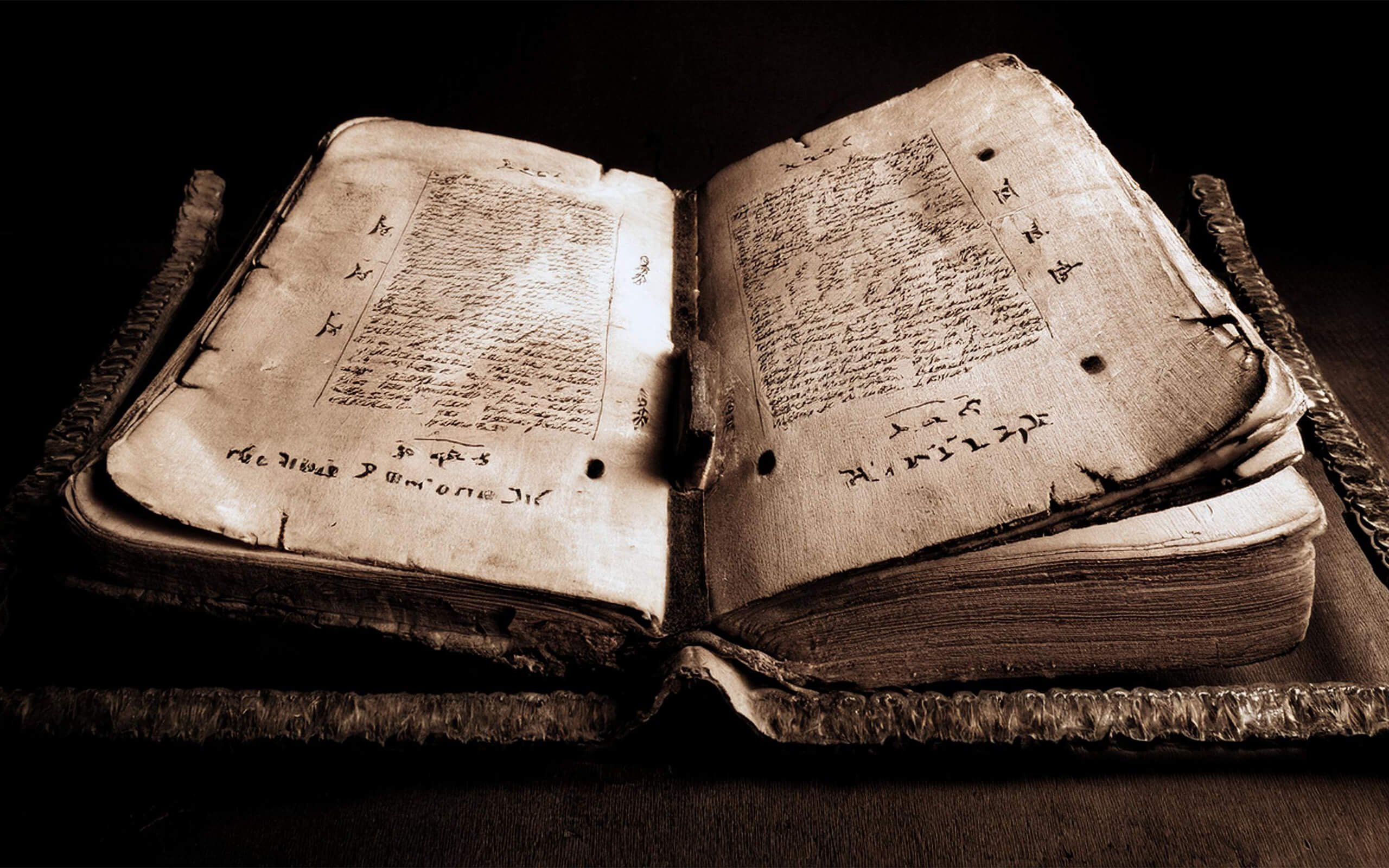 Offenes, antikes Buch mit handgeschriebenen Seiten und vergilbtem Papier, auf dunklem Hintergrund.