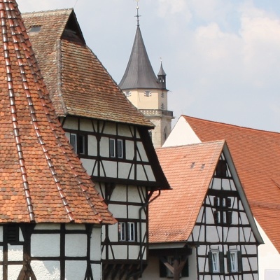 Fachwerkhäuser in Balingen mit roten Dächern und einem hohen Turm im Hintergrund.